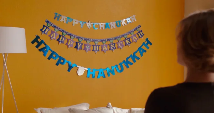 『クレイジー・エックス・ガールフレンド』で、壁に飾ったハヌカの文字を書いた３つの飾りを見つめるレベッカ