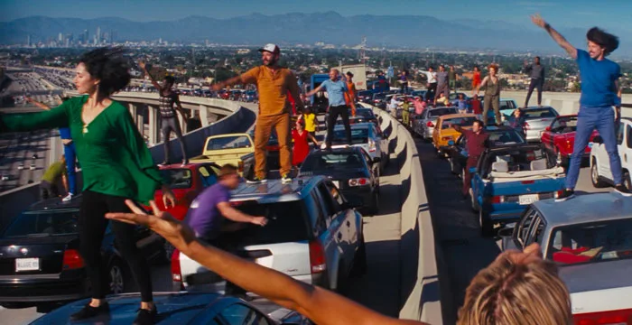 『ラ・ラ・ランド』で、緑色の服を着た車の上に立つ女性ダンサー