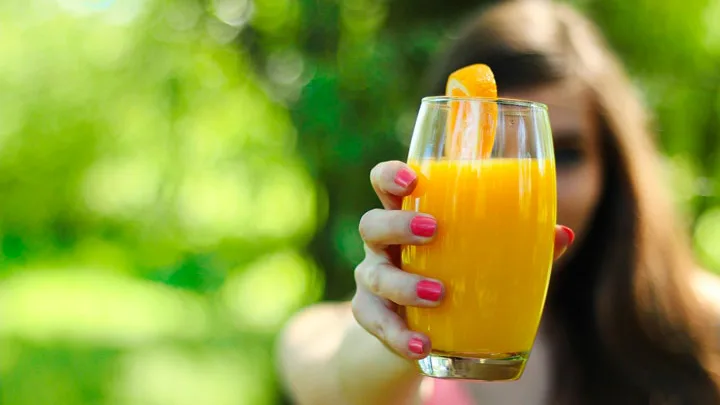 自然の中、女性がオレンジジュースを差し出す